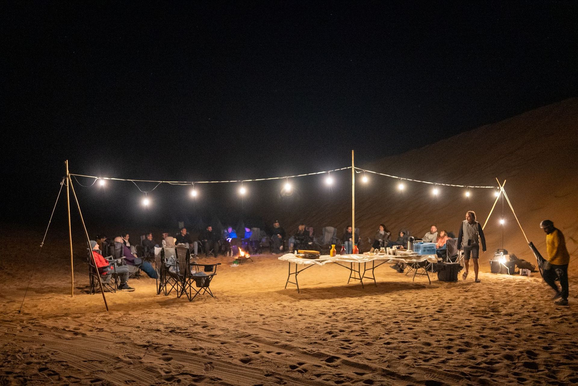 Group gathered under string lights below a starry sky at Al Quaa, Abu Dhabi